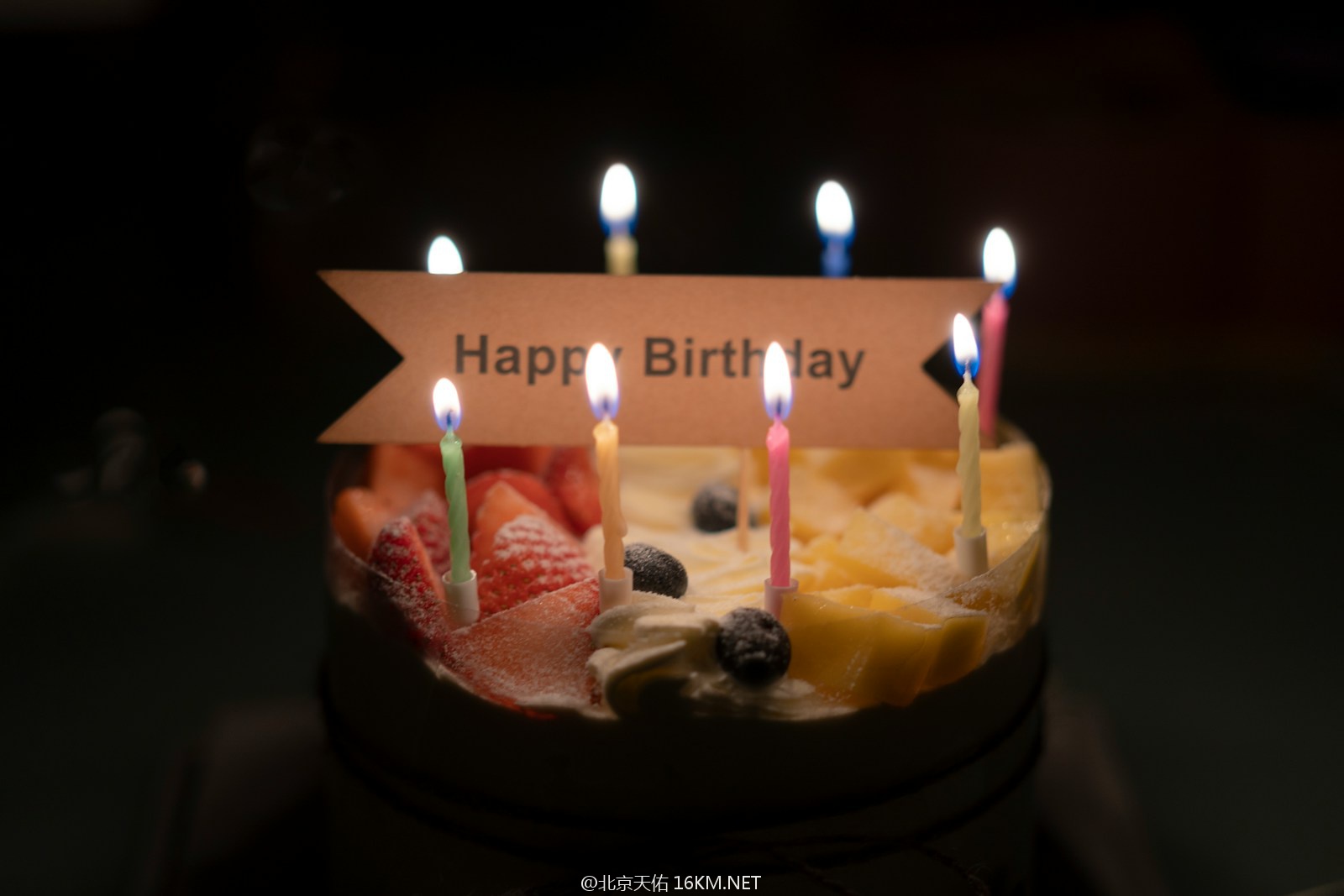 A birthday cake with candles and a sign that says happy birthday